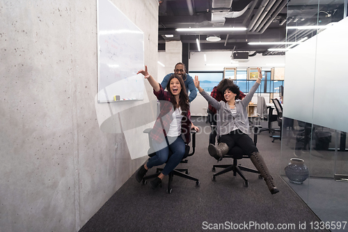 Image of multiethnics business team racing on office chairs