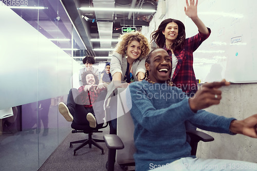 Image of multiethnics business team racing on office chairs