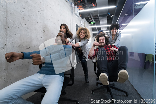 Image of multiethnics business team racing on office chairs