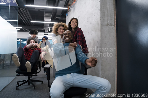 Image of multiethnics business team racing on office chairs