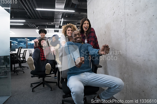 Image of multiethnics business team racing on office chairs