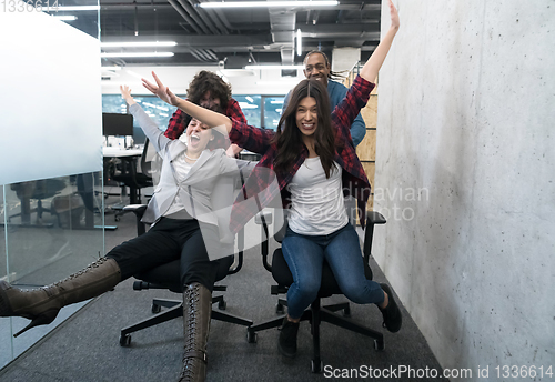 Image of multiethnics business team racing on office chairs