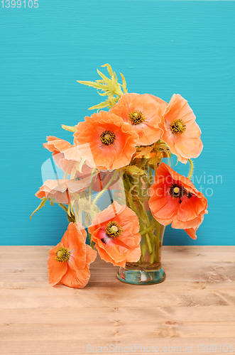 Image of Vase of pale pink poppies on a wooden table
