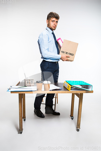 Image of The young man is resigned and folds things in the workplace