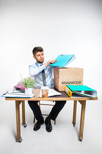 Image of The young man is resigned and folds things in the workplace