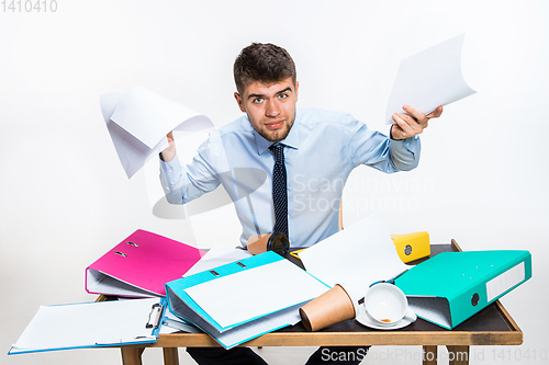 Image of The young man has a complete mess in the workplace, he cannot organize his space