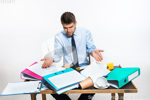 Image of The young man has a complete mess in the workplace, he cannot organize his space