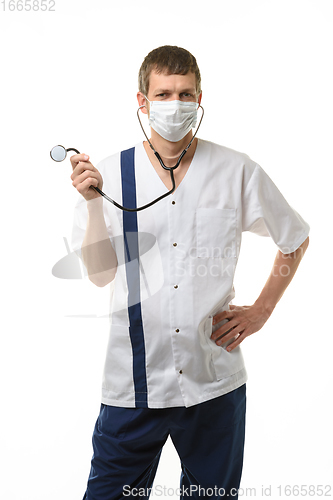 Image of Doctor in mask laughs and twirls a phonendoscope in his hand, isolated on white background