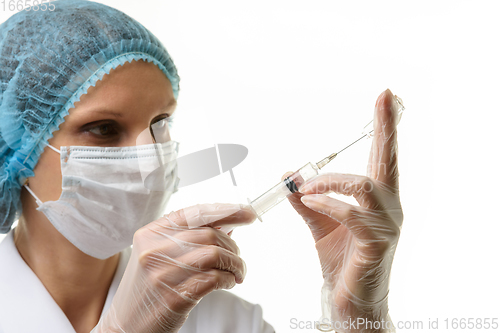 Image of A nurse wearing a mask and gloves draws medicine with a syringe from an ampoule, isolated on a white background