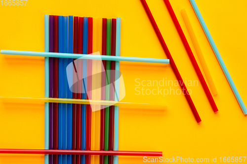 Image of Multi-colored cocktail tubes lie on a yellow background