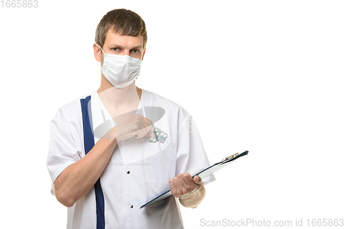 Image of The doctor stands with a tablet in his hand, with the other hand he pulls out medicines from the chest pocket