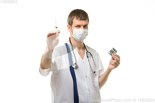 Image of Male doctor holding a syringe with medicine in one hand and pills in the other hand, isolated on white background