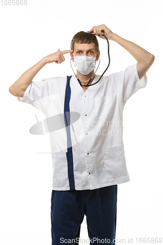 Image of A masked doctor with a phonendoscope listens to his head, with the other hand he applied an impromptu pistol to his temple, isolated on a white background