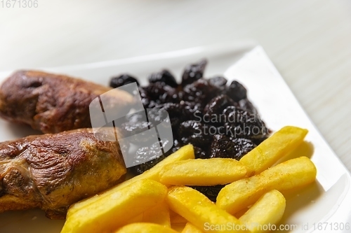 Image of Roast duck breast with plums and fries served on dish