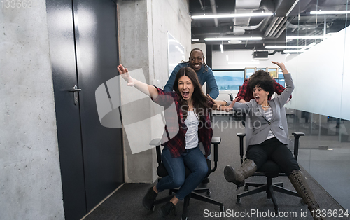 Image of multiethnics business team racing on office chairs