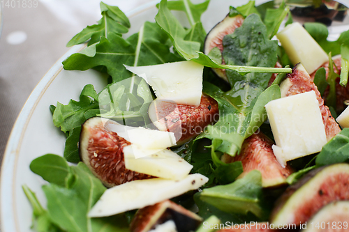 Image of Fresh fig and pecorino chunks on a bed of green rocket leaves