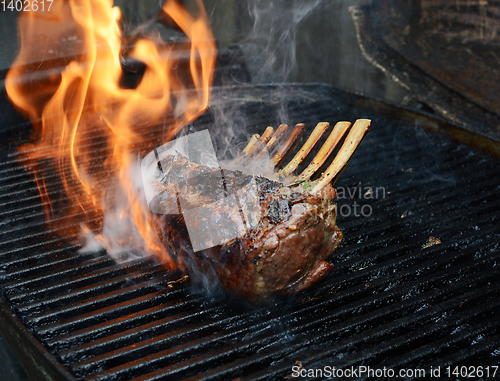 Image of Rack of lamb on barbecue with flame and smoke