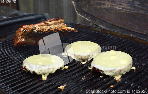 Image of Three cheeseburgers and a rack of lamb on a grill