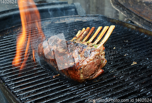 Image of Flame rises from a grill around barbecued meat