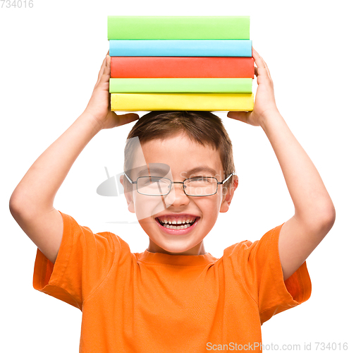 Image of Little boy is holding a pile of books