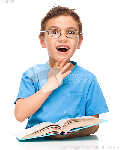 Image of Astonished little boy is reading a book