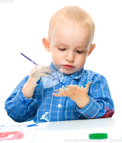 Image of Little boy is playing with paints