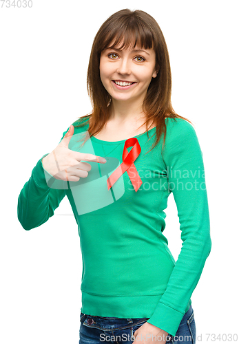 Image of Woman is pointing to the red awareness ribbon