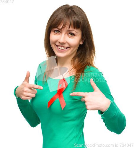 Image of Woman is pointing to the red awareness ribbon