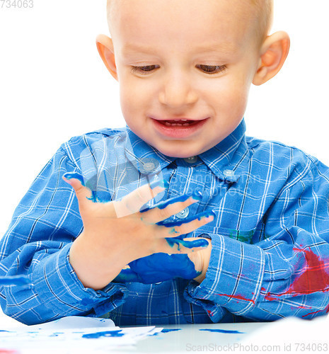 Image of Little boy is playing with paints