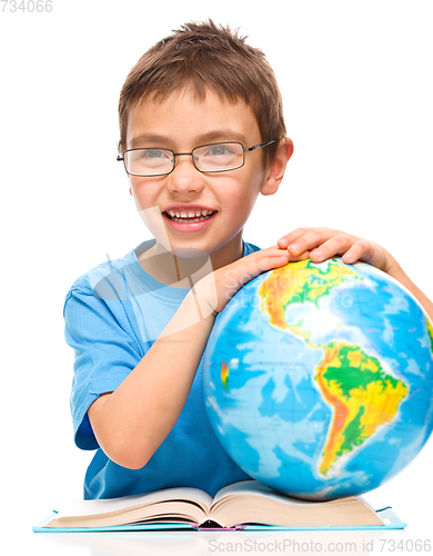 Image of Little boy is examining globe