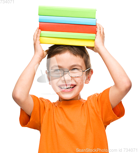 Image of Little boy is holding a pile of books