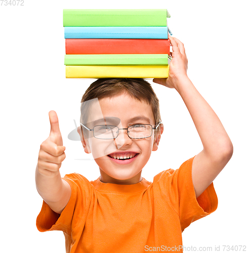 Image of Little boy is holding a pile of books