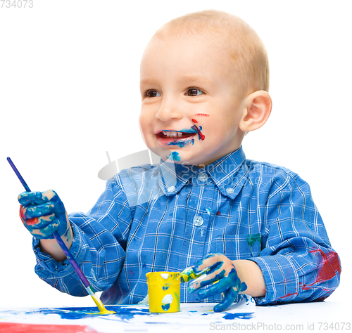 Image of Little boy is playing with paints