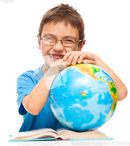 Image of Little boy is examining globe