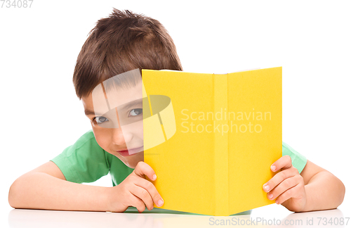 Image of Little boy plays with book