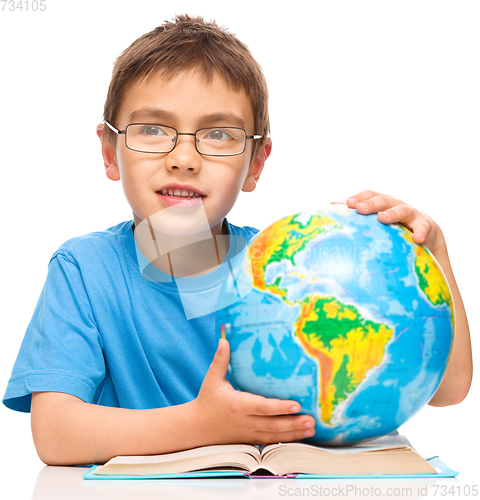 Image of Little boy is examining globe