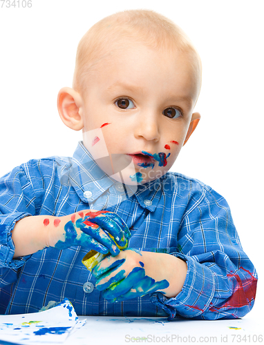 Image of Little boy is playing with paints