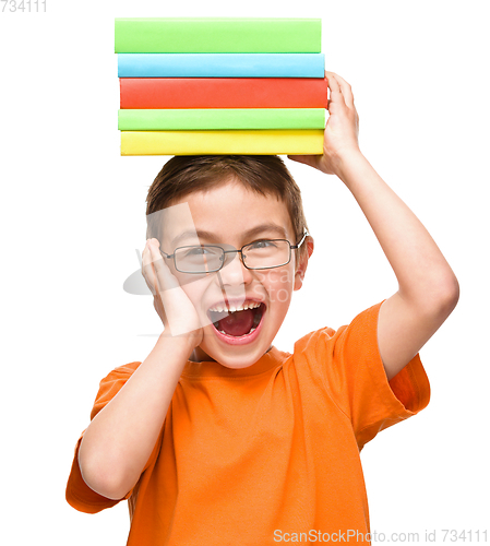 Image of Little boy is holding a pile of books