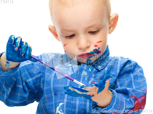 Image of Little boy is playing with paints