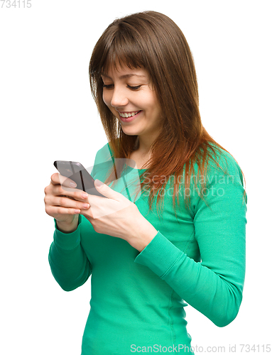 Image of Young woman is typing sms message on her phone