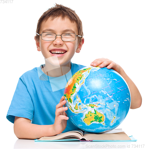 Image of Little boy is examining globe