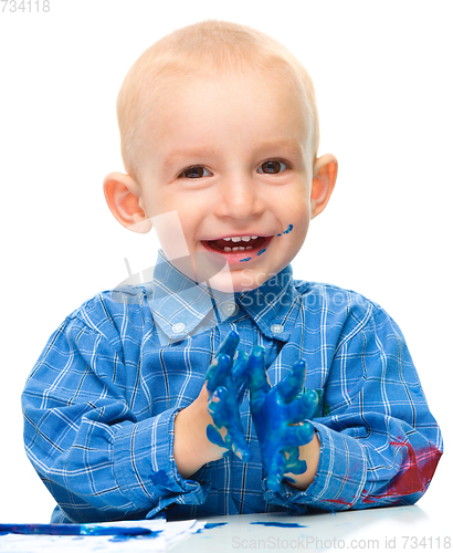 Image of Little boy is playing with paints