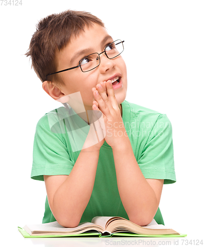 Image of Young boy is daydreaming while reading book