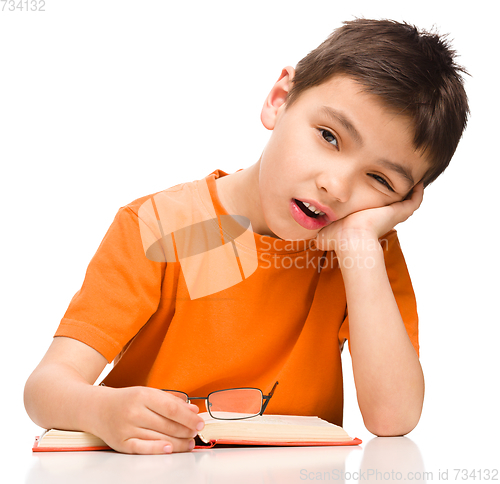 Image of Little boy is tired to read his book