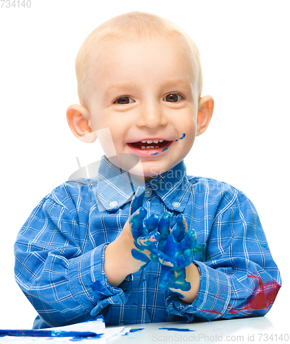 Image of Little boy is playing with paints