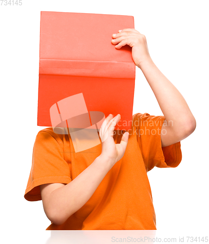 Image of Little boy is hiding behind a book