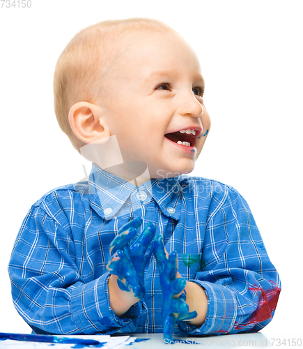 Image of Little boy is playing with paints