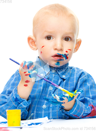 Image of Little boy is playing with paints