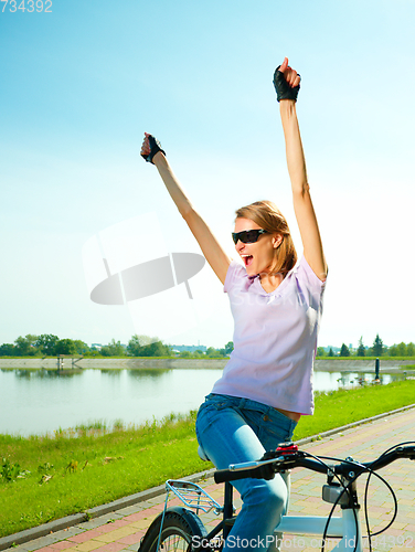 Image of Young woman is sitting on her bicycle