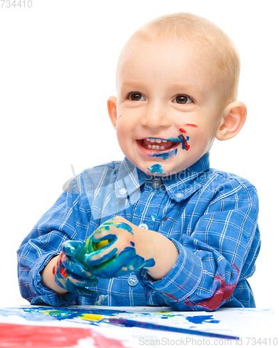 Image of Little boy is playing with paints